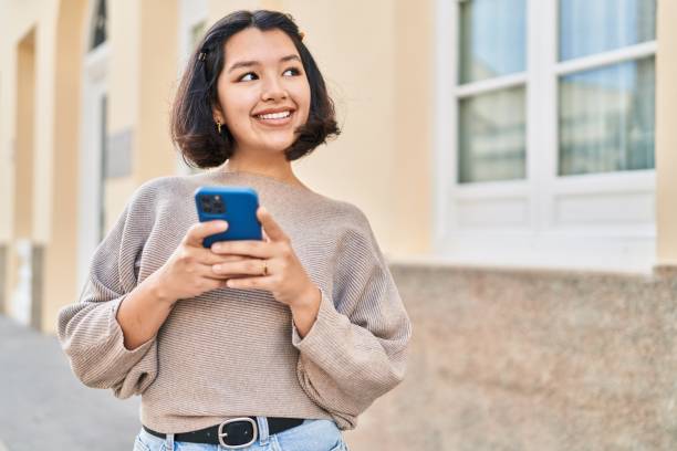 istock Young woman smiling confident using smartphone at street 1437889497