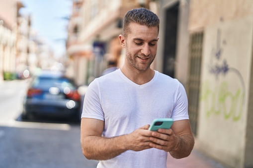 Young caucasian man smiling confident using smartphone at street