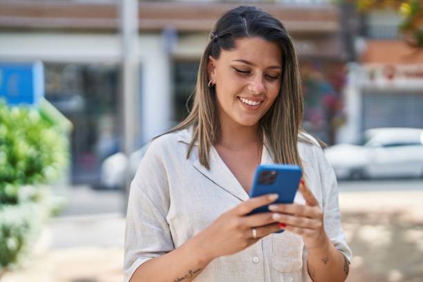 istock Young hispanic woman smiling confident using smartphone at street 1437895258