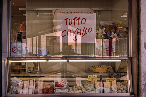 Venice, Italy - October 12th 2022:  Window of a butchers shop with a poster telling that all the meat is horse meat in the center of the old and famous Italian city Venice