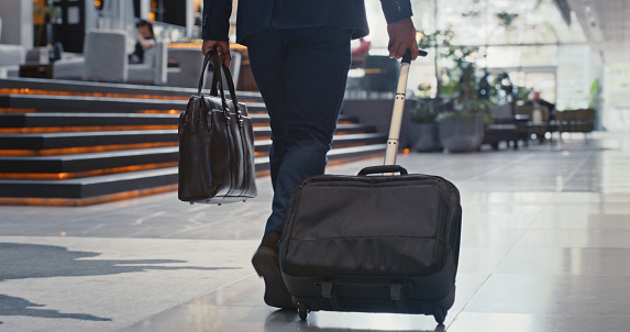 Businessman, luggage and travel while walking in airport or station for company trip or international flight. Corporate person with international traveling, suitcase and employee in airport terminal