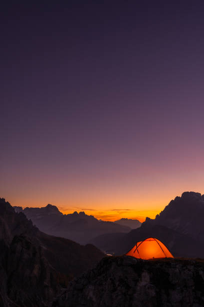 Evening twilight after sunset in alpine mountains with lit tent