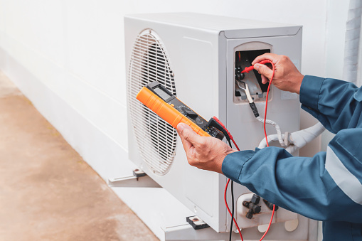 Air conditioner technician repairing central air conditioning system with outdoor tools