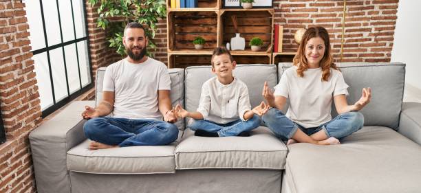 istock Family doing yoga exercise sitting on sofa at home 1437896778