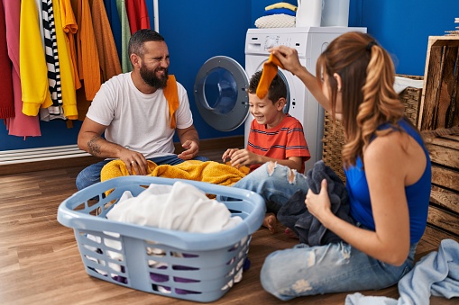 Family smiling confident playing with clothes at laundry room