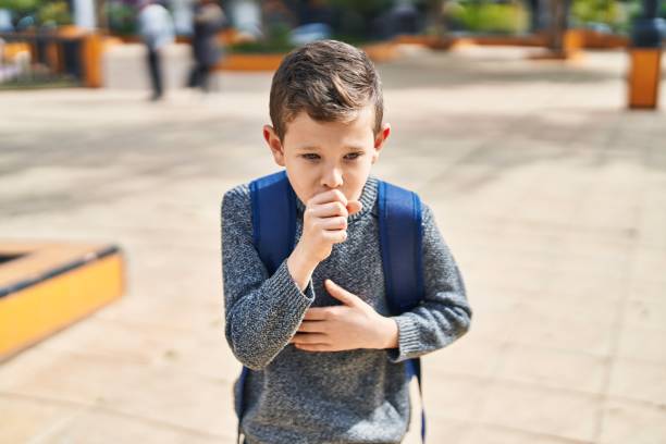 Blond child student coughing at park stock photo
