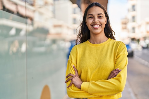 Young african american woman smiling confident standing with arms crossed gesture at street