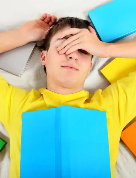 Tired Teenager sleep with a Books on the Bed