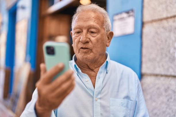istock Senior grey-haired man using smartphone at street 1437903265