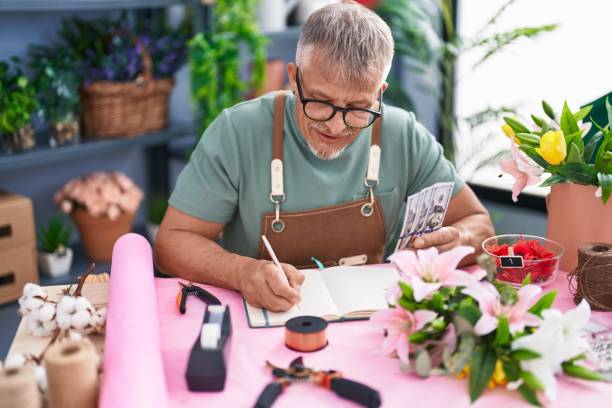 花屋でノート��に書くドルを数える中年の白髪の男の花屋 - flower shop flower flower market store ストックフォトと画像