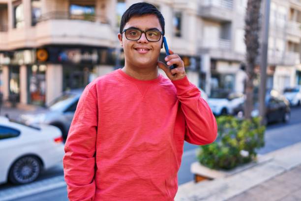 Down syndrome man smiling confident talking on the smartphone at street stock photo
