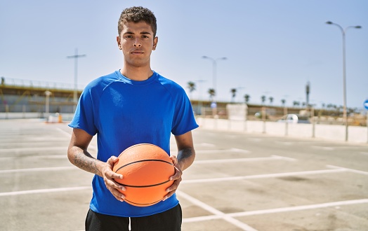 Young hispanic man training with basketball ball outdoors