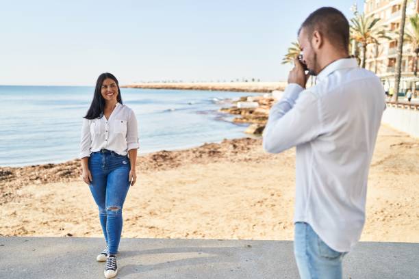 istock Man and woman couple smiling make photo using camera at seaside 1437906022