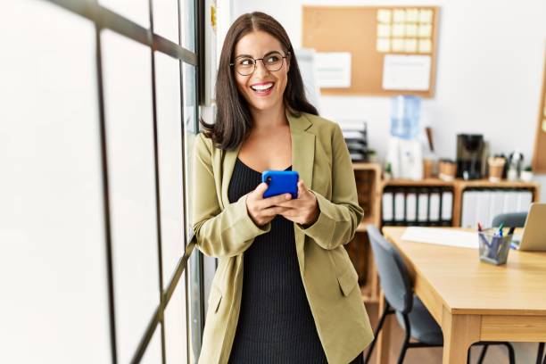 istock Young beautiful hispanic woman business worker smiling confident using smartphone at office 1437906759