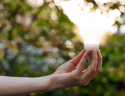 Close up on a woman hand holding a lightened light bulb.