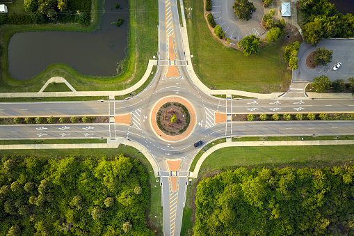 Aerial view of road roundabout intersection with moving cars traffic. Rural circular transportation crossroads.