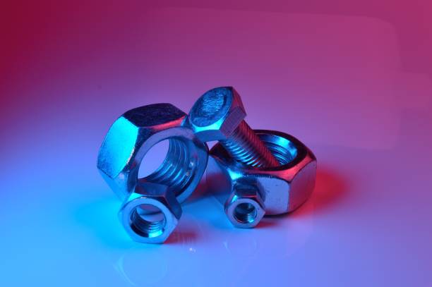 istock large and small nuts and bolts, highlighted in different colors, on a light background. 1437909566