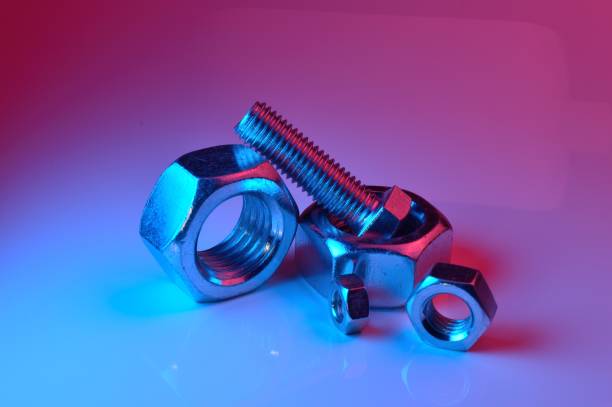 istock large and small nuts and bolts, highlighted in different colors, on a light background. 1437909583