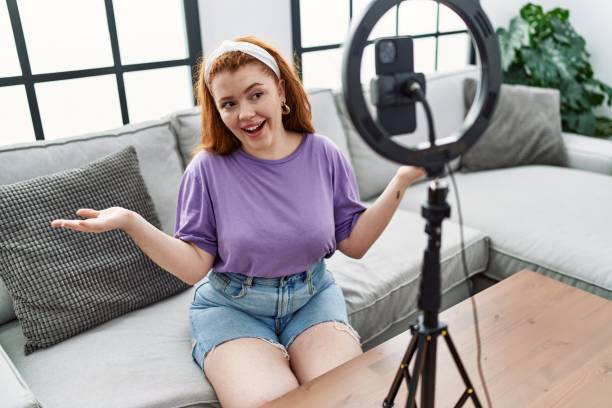 istock Young redhead woman having video call using smartphone at home 1437910328
