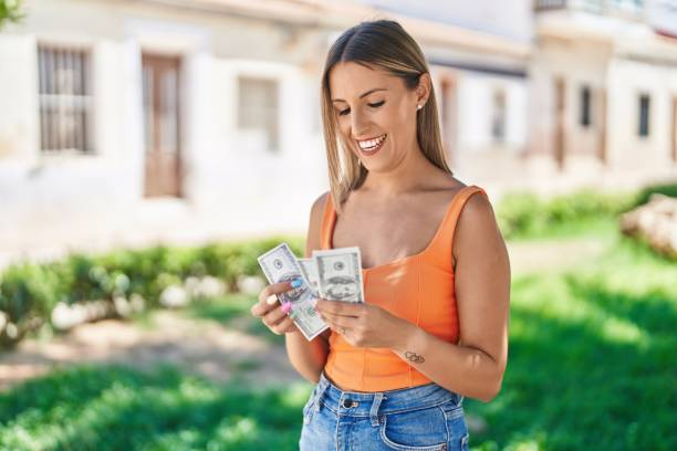 Young beautiful hispanic woman smiling confident counting dollars at park stock photo