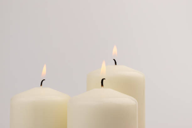 istock Burning white wax candles on white background. 1437912733