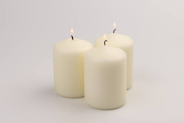istock Burning white wax candles on white background. 1437912747