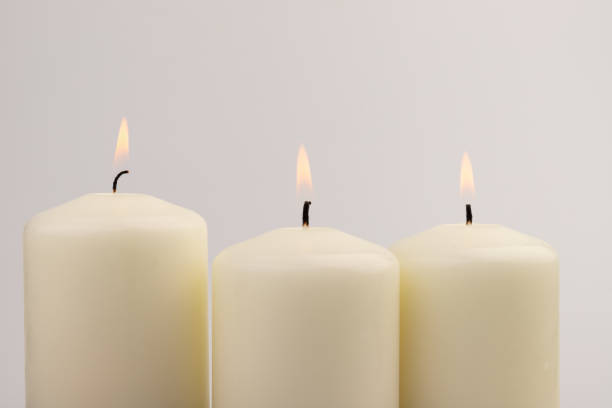 istock Burning white wax candles on white background. 1437912798