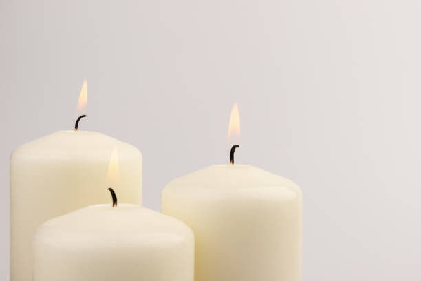 istock Burning white wax candles on white background. 1437912801