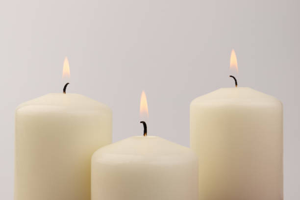 istock Burning white wax candles on white background. 1437912802
