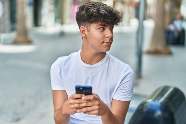 istock Young hispanic teenager using smartphone with relaxed expression at street 1437912820