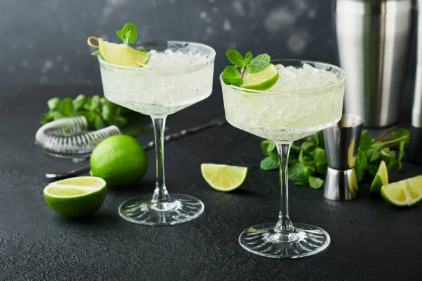 istock Margarita cocktail with lime, tequila, mint and ice on dark table with amazing backlight, copy space. Classic Margarita or Daiquiry Cocktail. Bar card or counter concept. Selective or soft focus. 1437912851