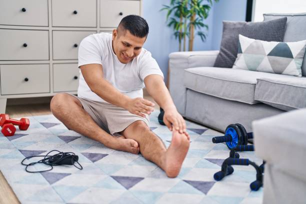 istock Young latin man smiling confident stretching leg at home 1437914867