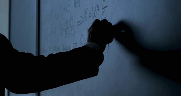 scientifique écrivant des formules au tableau. main à la craie a écrit des formules physiques sur un tableau noir en gros plan - formula blackboard complexity scientist photos et images de collection