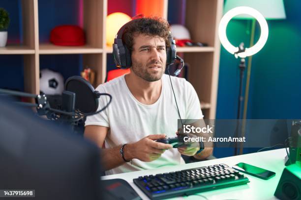 Young Hispanic Man Streamer Playing Video Game Using Joystick At Music Studio Stock Photo - Download Image Now