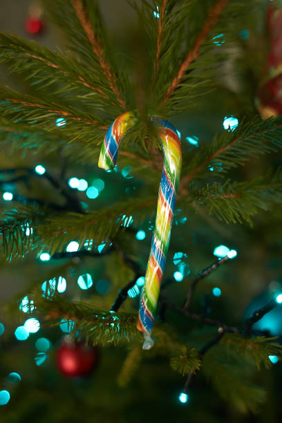 крупным планом праздничные электрические синие гирлянды на еловой ветке с елочным украшением и конфетно-сладкими. конфетная трость, висящ� - candy cane flash стоковые фото и изображения