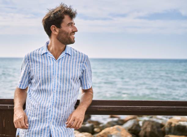 istock Young hispanic man smiling happy standing at the beach. 1437915780