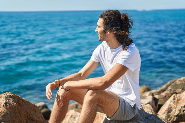 istock Young hispanic man breathing with closed eyes at seaside 1437917097