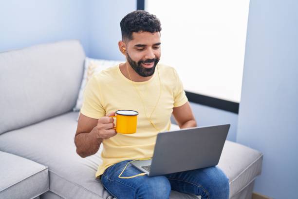 istock Young arab man using laptop drinking coffee at home 1437917534