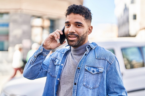 handsome businessman giving a thumbs up and talking on the phone against white background