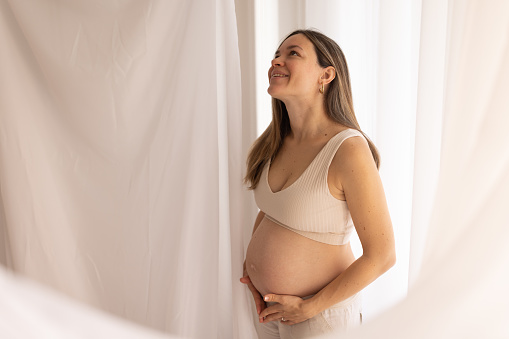 One woman, beautiful happy pregnant woman touching her belly.