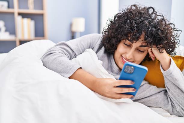 istock Young middle east woman using smartphone lying on bed at bedroom 1437919138