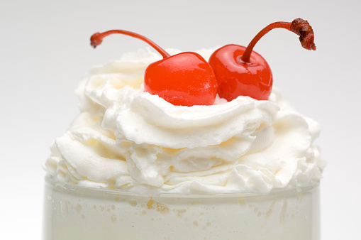 Vanilla milkshake with whipped cream, and cherries.
