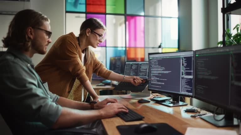 Female Data Scientist and Male Developer Improving Code on Desktop Computer in Stylish Office. Caucasian Man And Woman Creating Service as a Software Platform for Innovative Technological Start-Up.