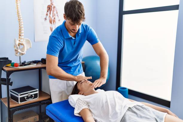 man and woman wearing physiotherpy uniform having reiki therapy session at clinic - reiki alternative therapy massaging women imagens e fotografias de stock