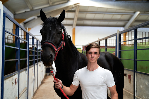 A young Caucasian male posing with his horse before a riding class