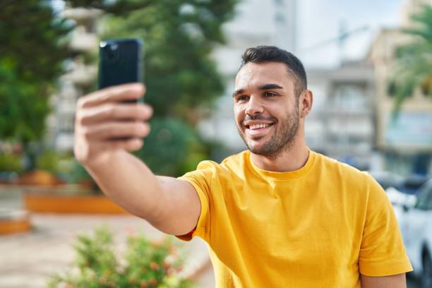istock Young hispanic man smiling confident making selfie by the smartphone at park 1437923379