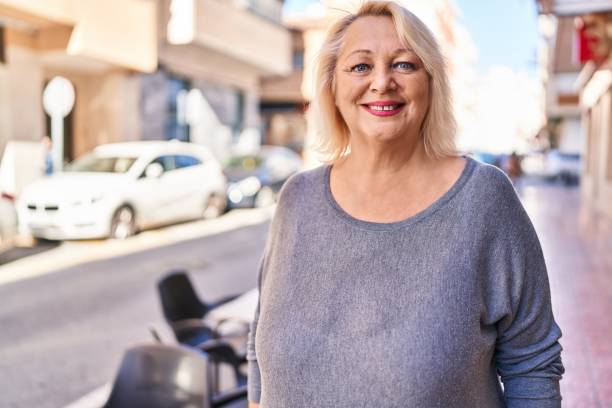 通りに立って自信を持って微笑む中年の金髪の女性 - senior women cheerful overweight smiling ストックフォトと画像