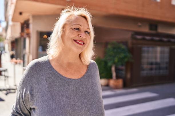 通りに立って自信を持って微笑む中年の金髪の女性 - senior women cheerful overweight smiling ストックフォトと画像