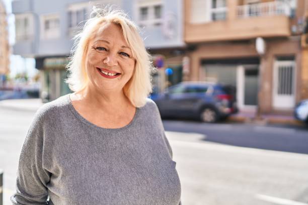 通りに立って自信を持って微笑む中年の金髪の女性 - senior women cheerful overweight smiling ストックフォトと画像
