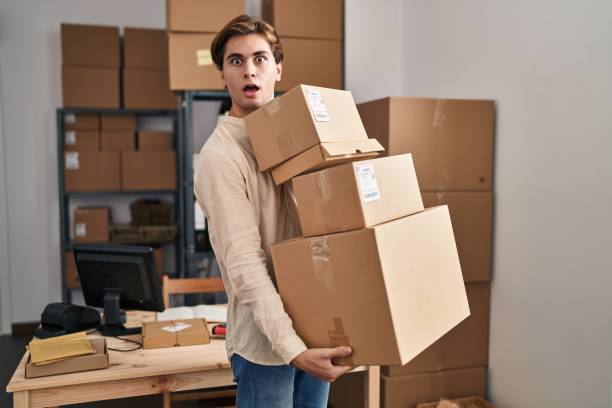 istock Young man working at small business ecommerce holding packages afraid and shocked with surprise and amazed expression, fear and excited face. 1437924426
